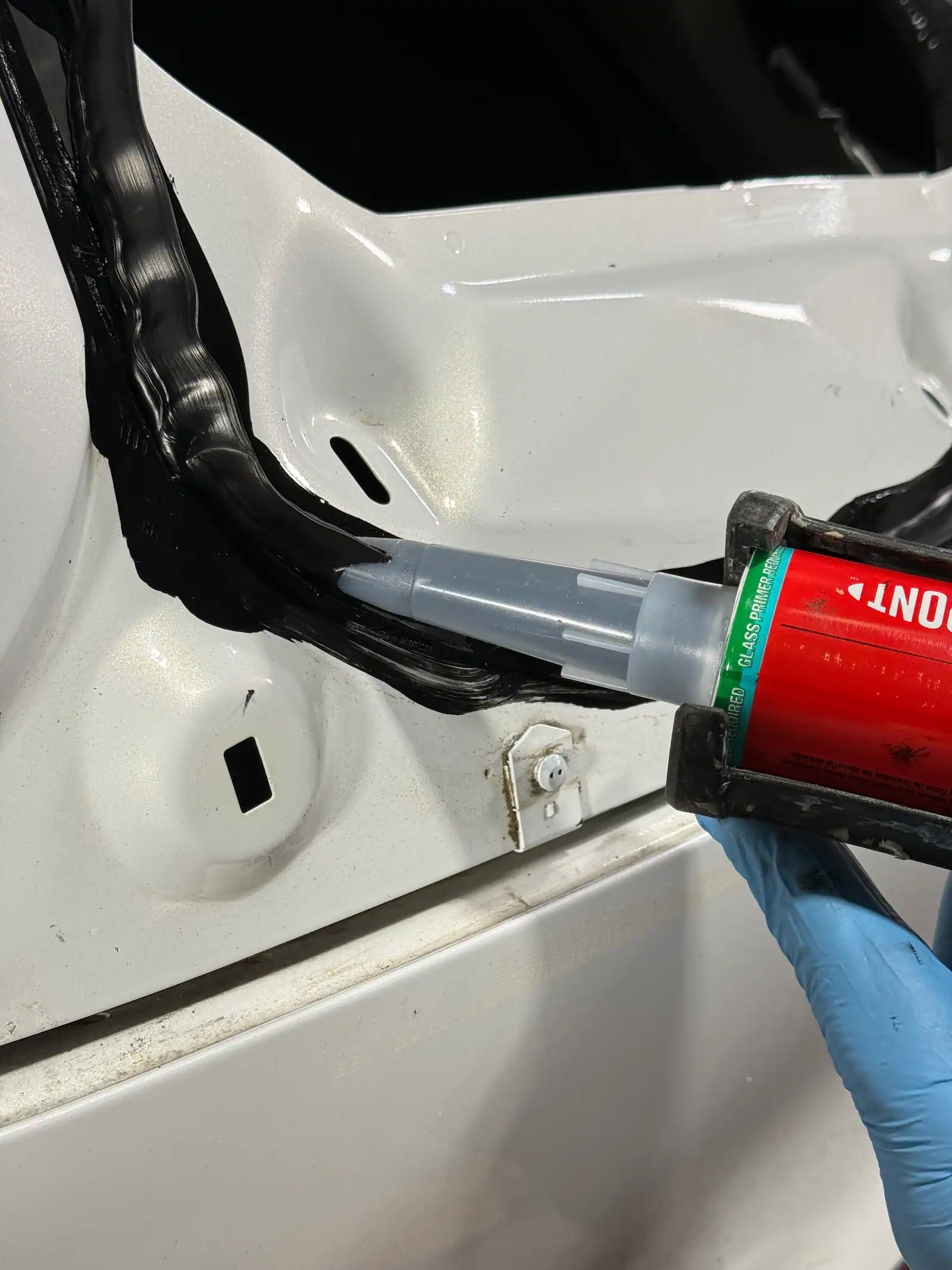 Applying automotive urethane adhesive during rear glass replacement at 123 Glass Company in Omaha