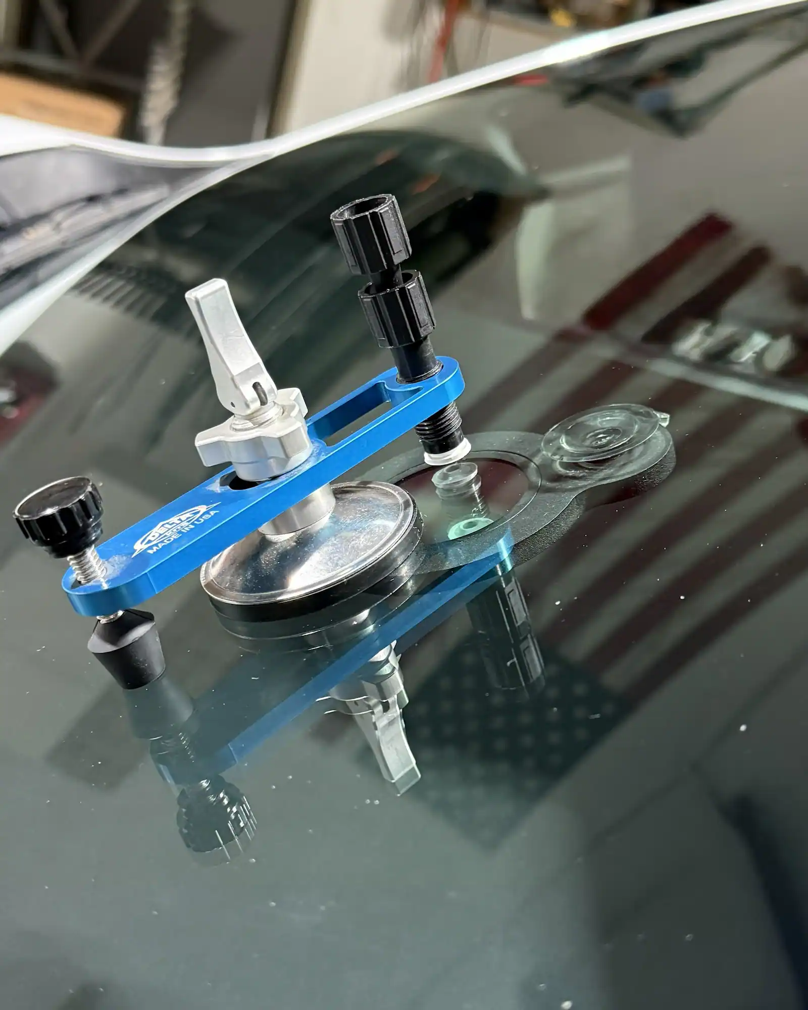 Windshield chip repair bridge mounted on a vehicle in the 123 Glass Company shop.